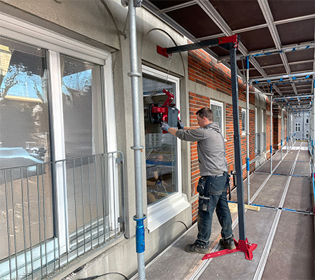 Fönstermontör använder Upclimber elektrisk glaslyft vid montage från byggställning